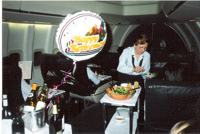 1980s Purser, Peggy Catalano, begins her last roundtrip from New York to Rome before retiring.  The crew tried to make this trip as memorable as possible  with balloons & banners on board.  Here Peggy serves salad from the cart in the First Class Cabin of a Pan Am 747 en route to Rome.